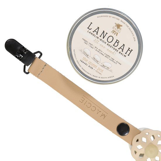 A wooden baby pacifier clip in a light natural wood finish with a black clip, shown next to its round silver tin packaging labeled 'LANOBAH'.