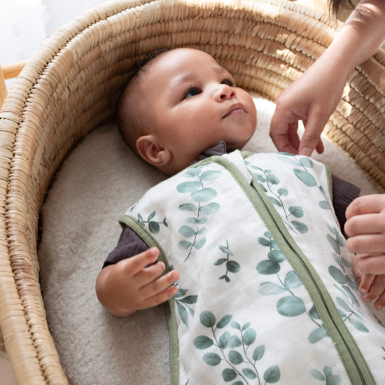 Baby lying in a woven crib with a floral patterned blanket