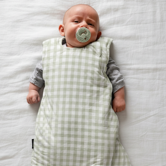 Baby wrapped in a green checkered swaddle on a black background