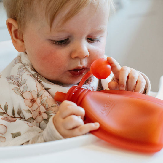 Child playing with a red toy in a kitchen setting