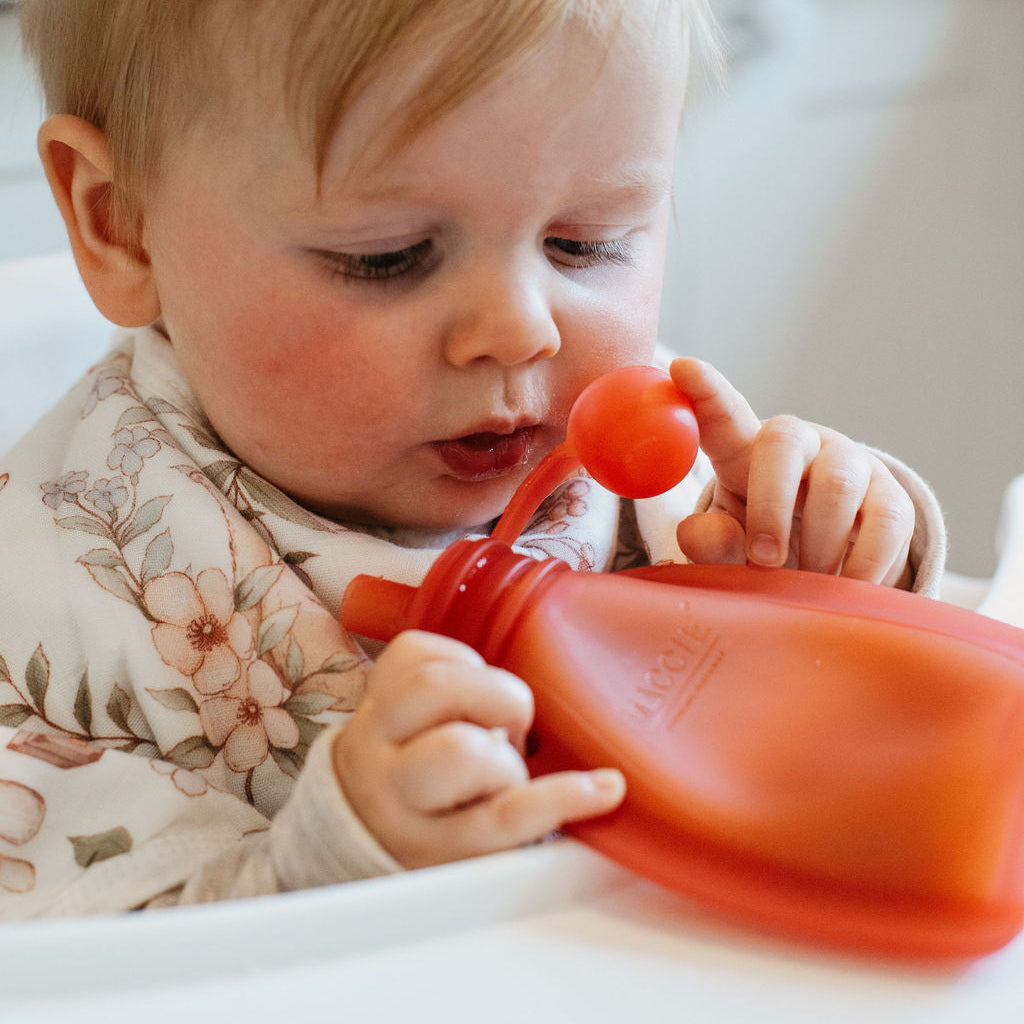 Child playing with a red toy in a kitchen setting