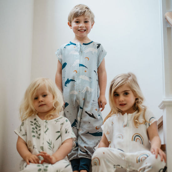 Three children in pajamas sitting on a staircase.