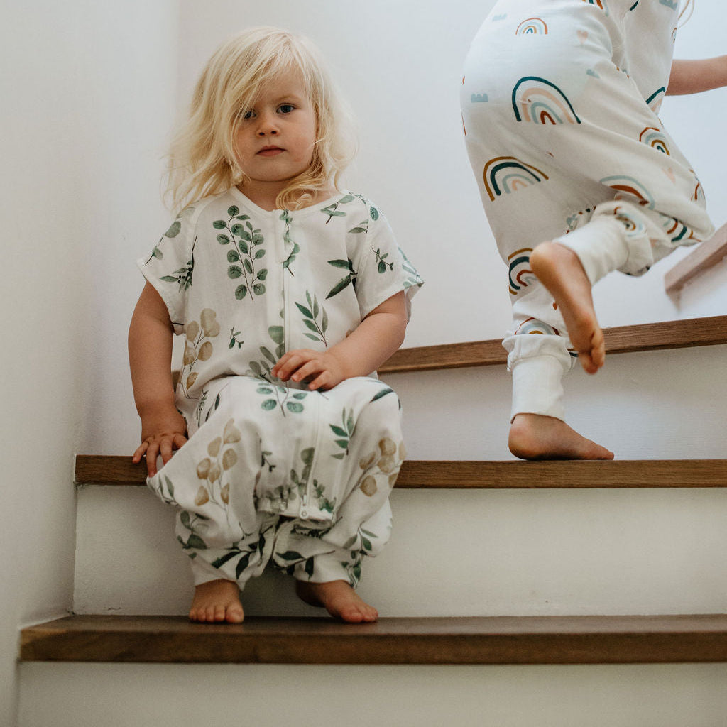 Two children in matching pajamas sitting on a staircase.