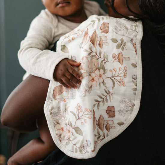 Woman holding a baby with a floral-patterned bib