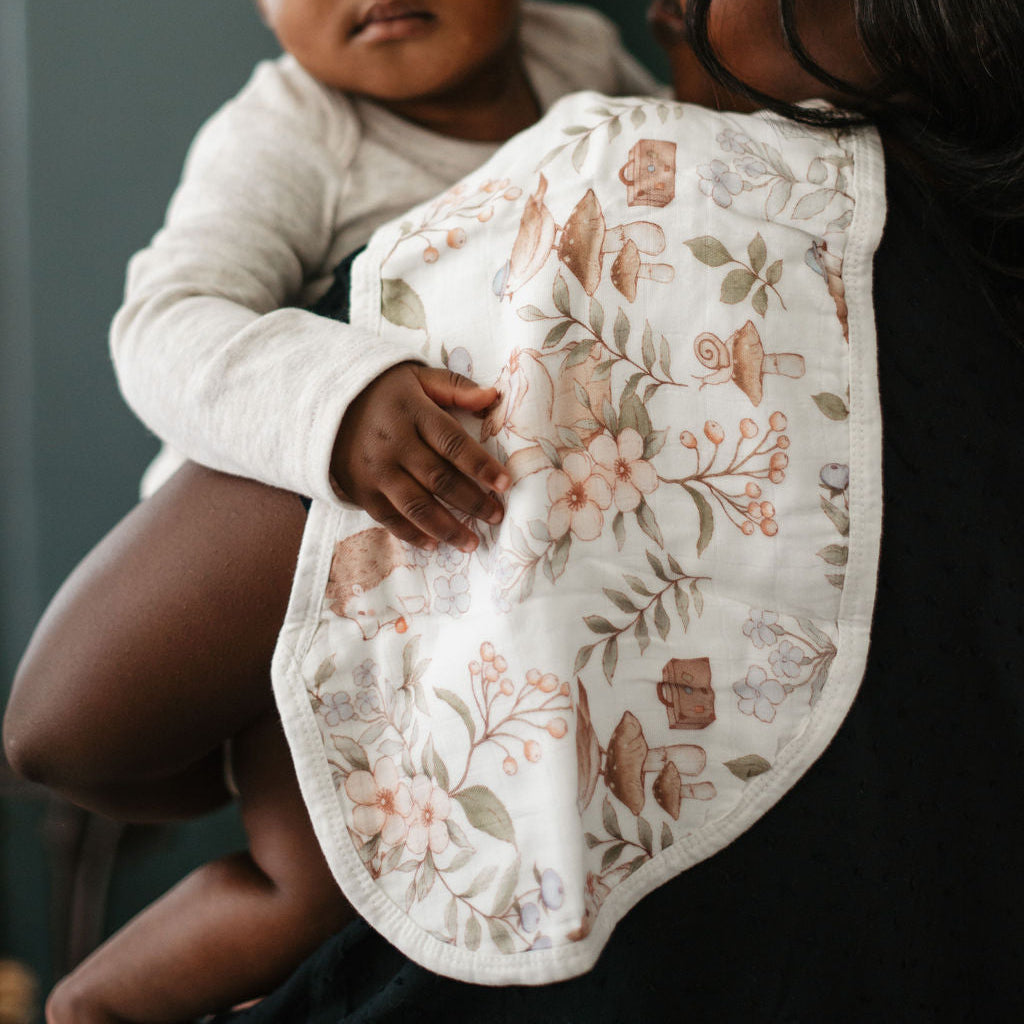 Woman holding a baby with a floral-patterned bib