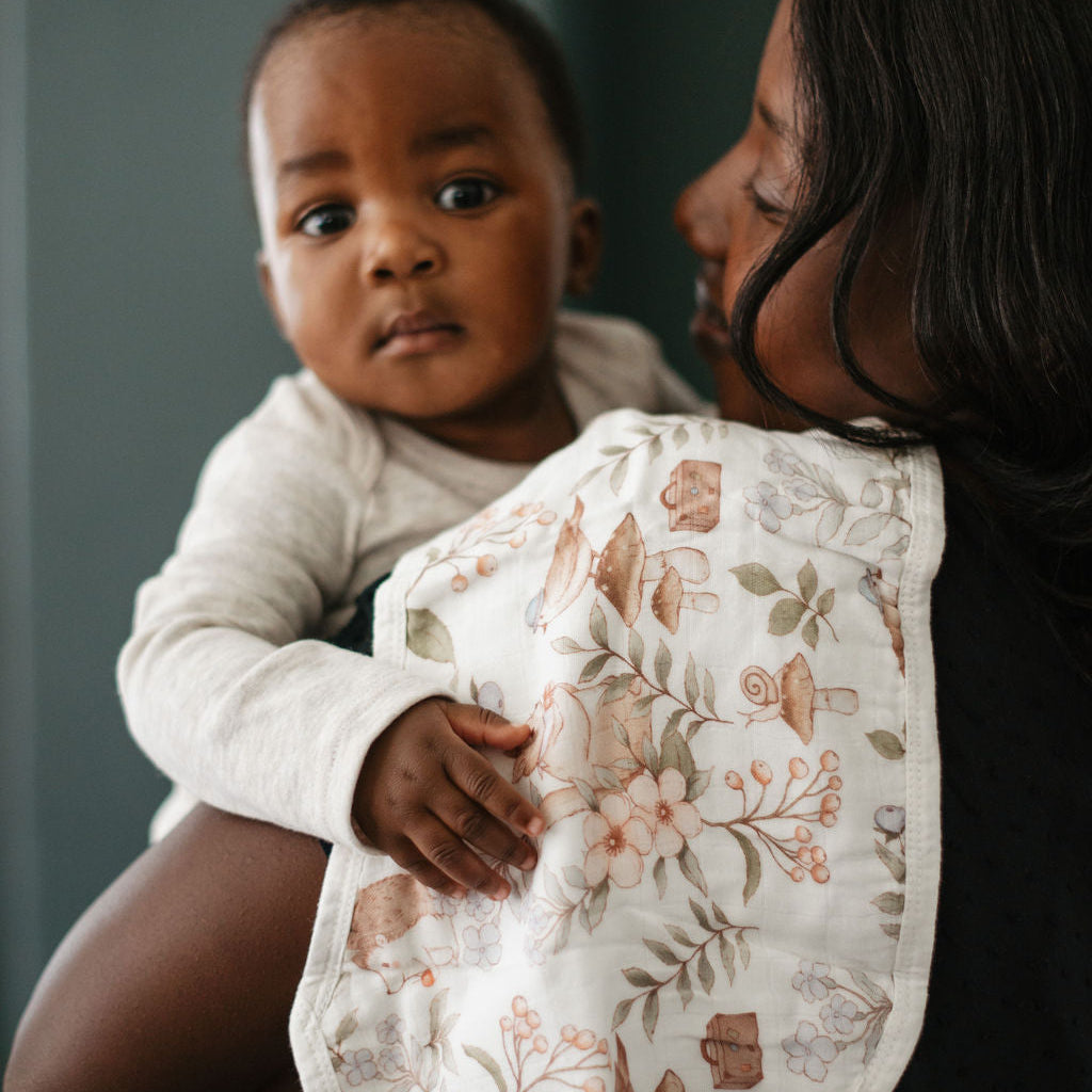 Woman holding a baby with a floral-patterned bib