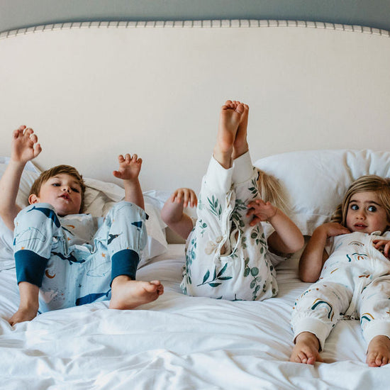 Three children in pajamas lying on a bed