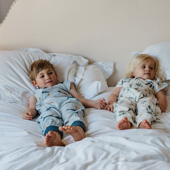 Three children lying on a bed wearing matching pajamas.