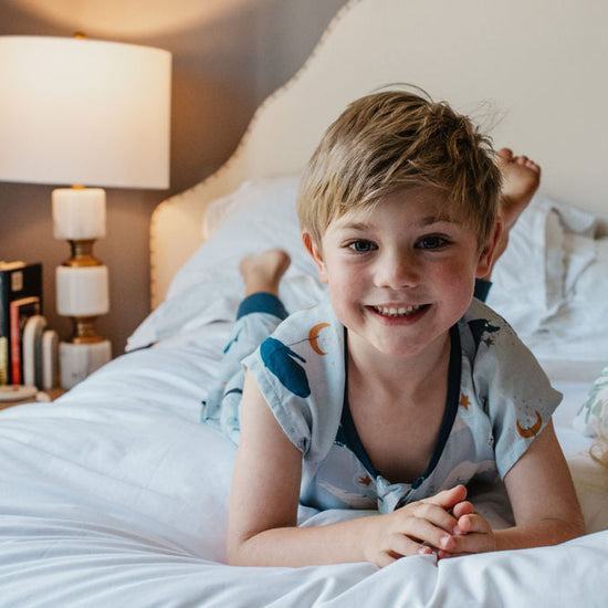 Two children lying on a bed in a bedroom setting.
