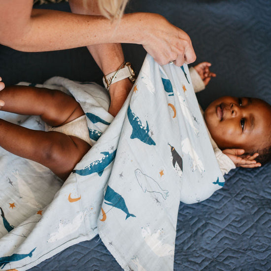 Baby lying on a blue textured surface with a patterned blanket