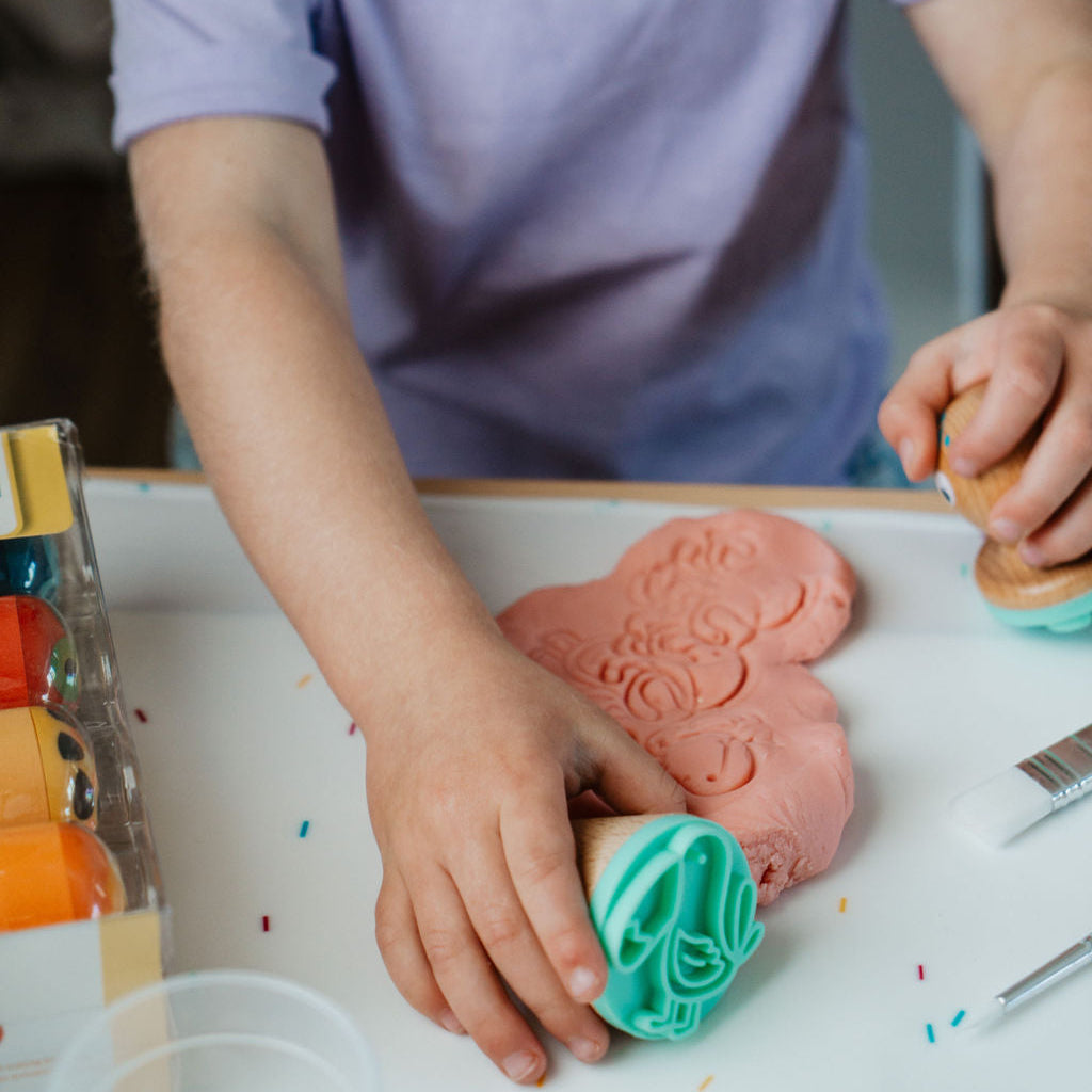 Child playing with play dough and tools on a table