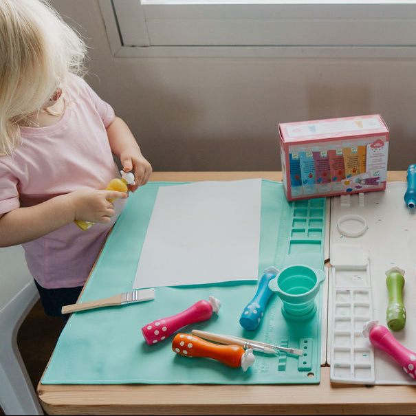 Two children playing with colorful toys at a table indoors.