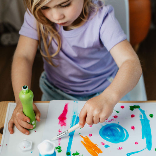 Child painting on a paper with colorful paint