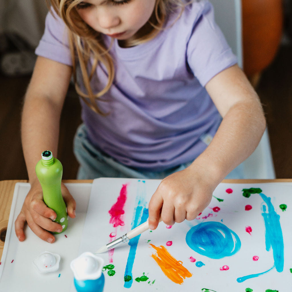Child painting on a paper with colorful paint