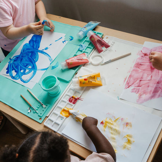 Children engaged in art activities at a table with various art supplies.