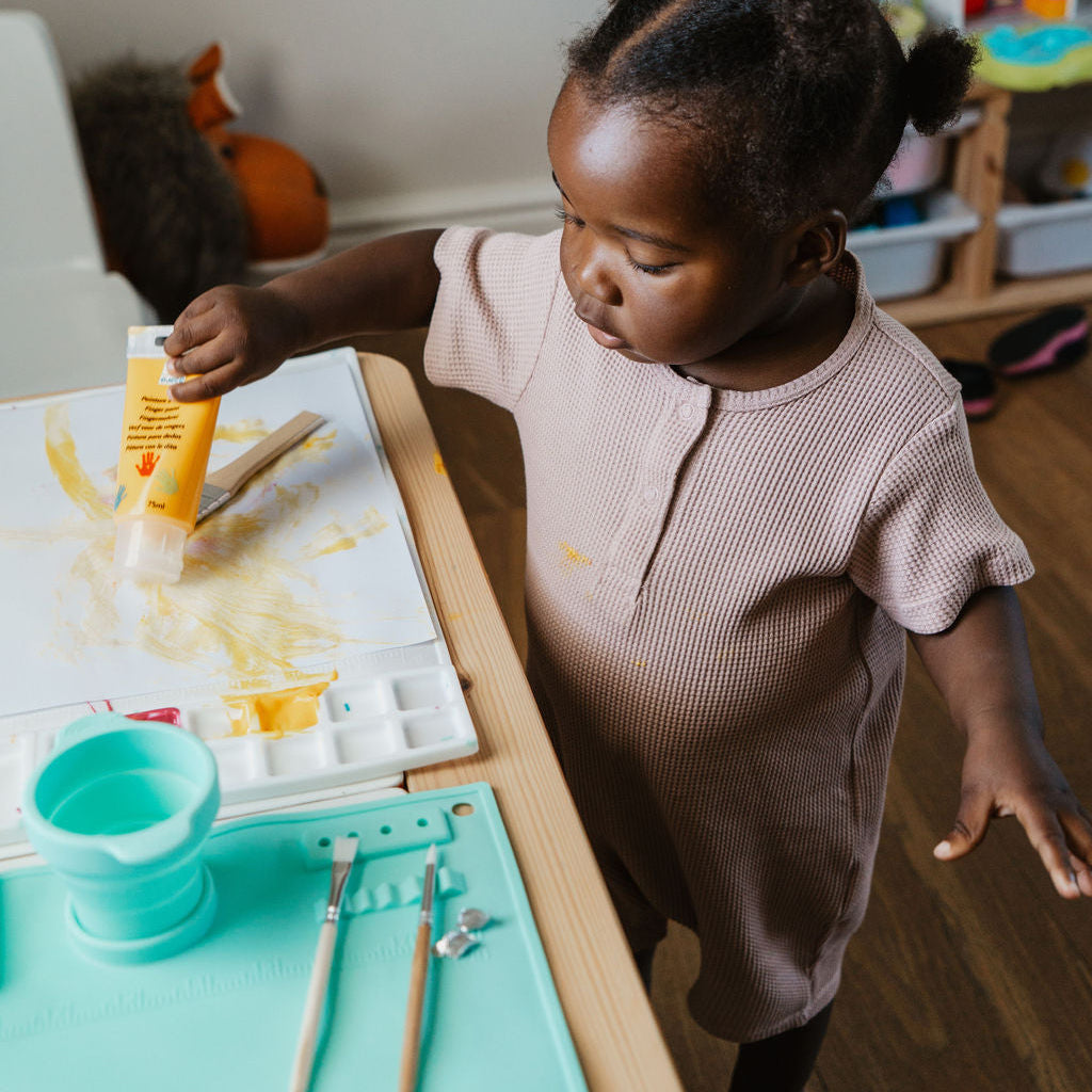 Child painting at a table with art supplies