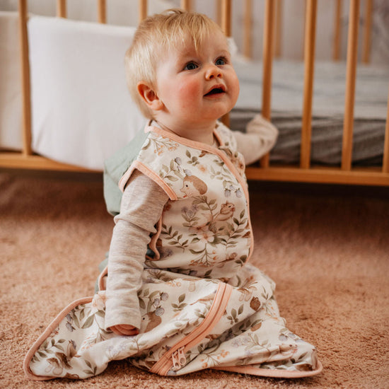 Baby sitting on a carpeted floor in a crib room
