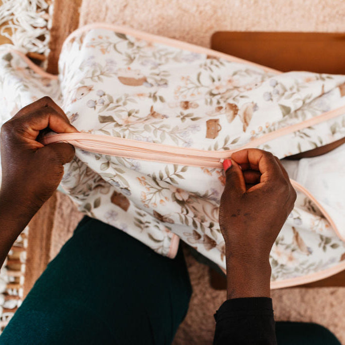Person holding a floral-patterned fabric over a baby crib