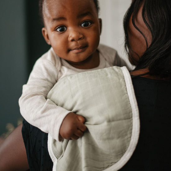 Baby being held by an adult wearing a white bib