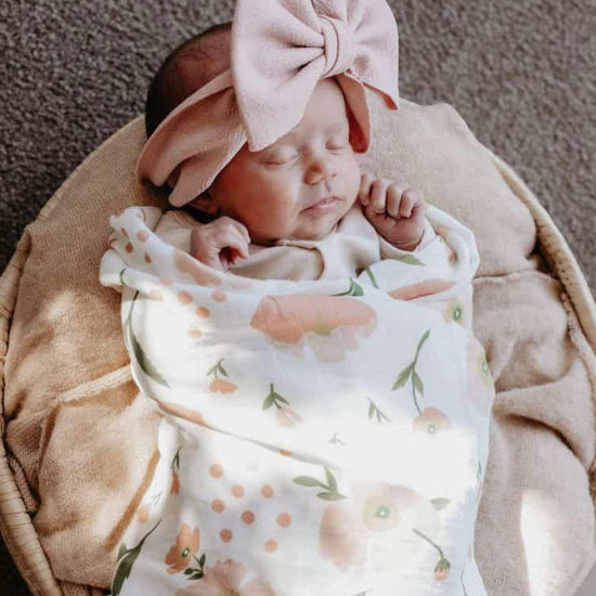 Newborn baby wrapped in a floral blanket on a soft surface