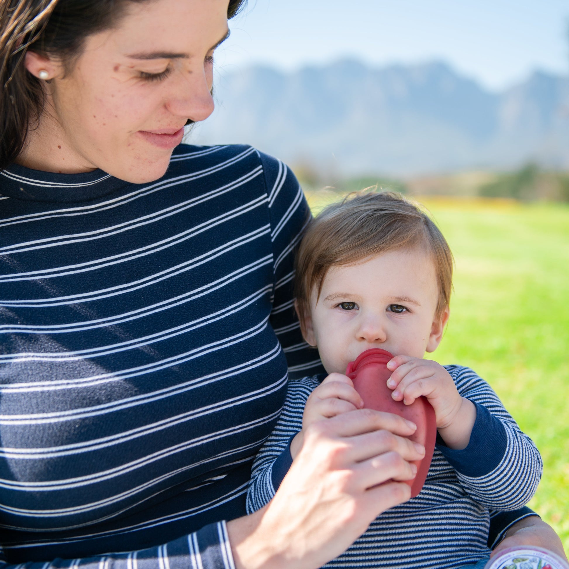 Woman holding a baby outdoors with a scenic background
