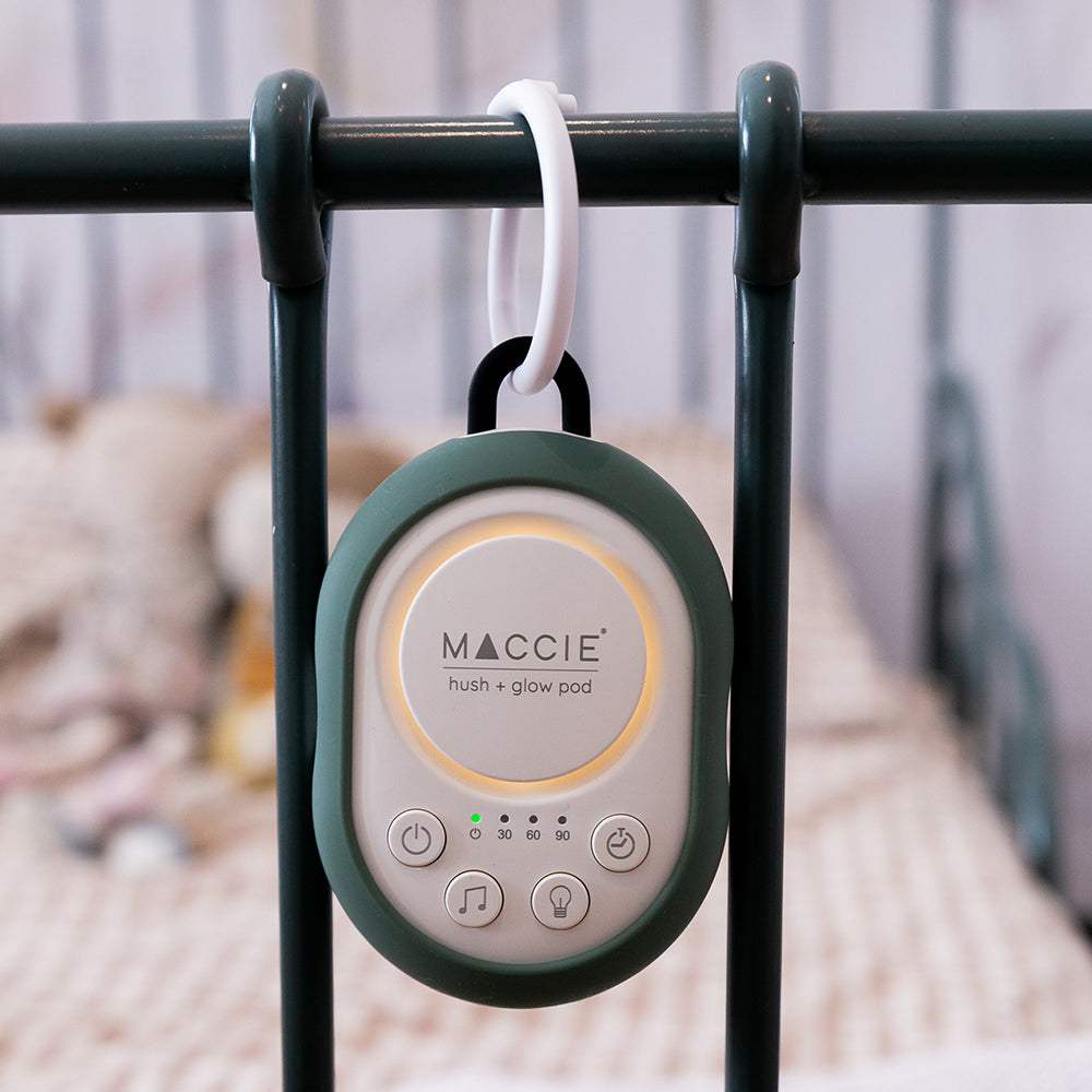 Maccie hush + glow pod hanging on a crib bar with a blurred background