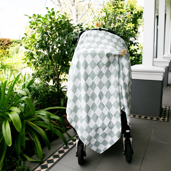 Stroller with a green and white checkered cover on a patio