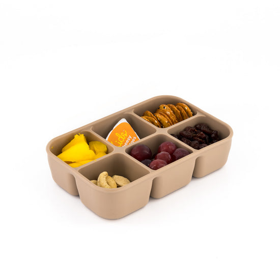 Toddler or child holding the small, square MACCIE cube snack box filled with healthy snacks like berries, cheese, and crackers, suitable for car or travel.