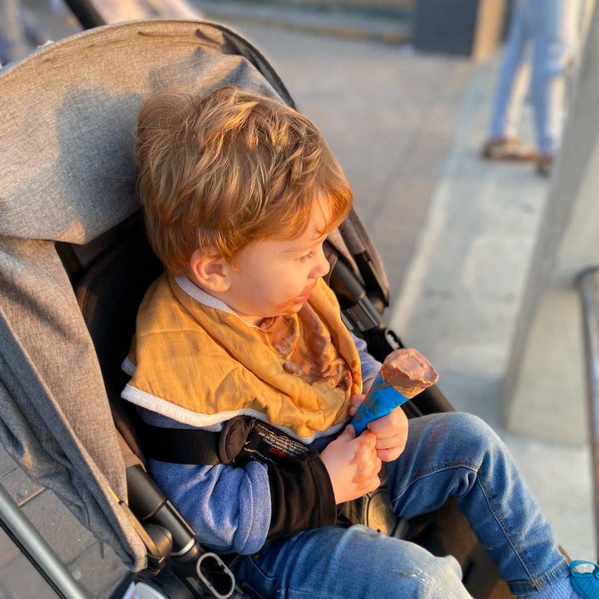 Child sitting in a stroller on a city street