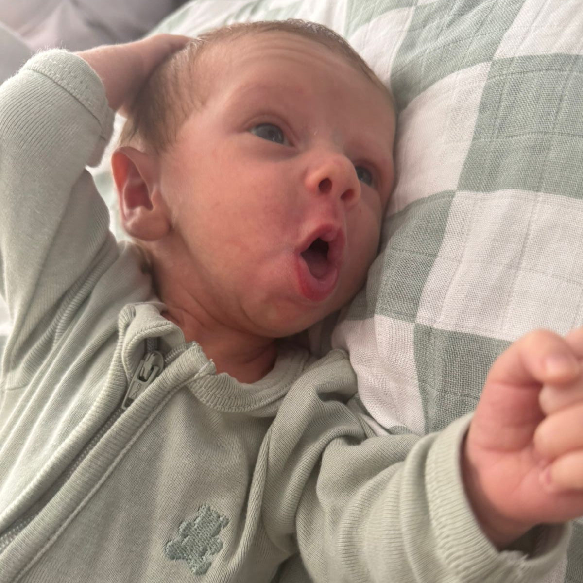 Newborn baby lying on a checkered blanket