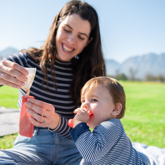 Woman and child sitting on grass outdoors, enjoying a drink together.